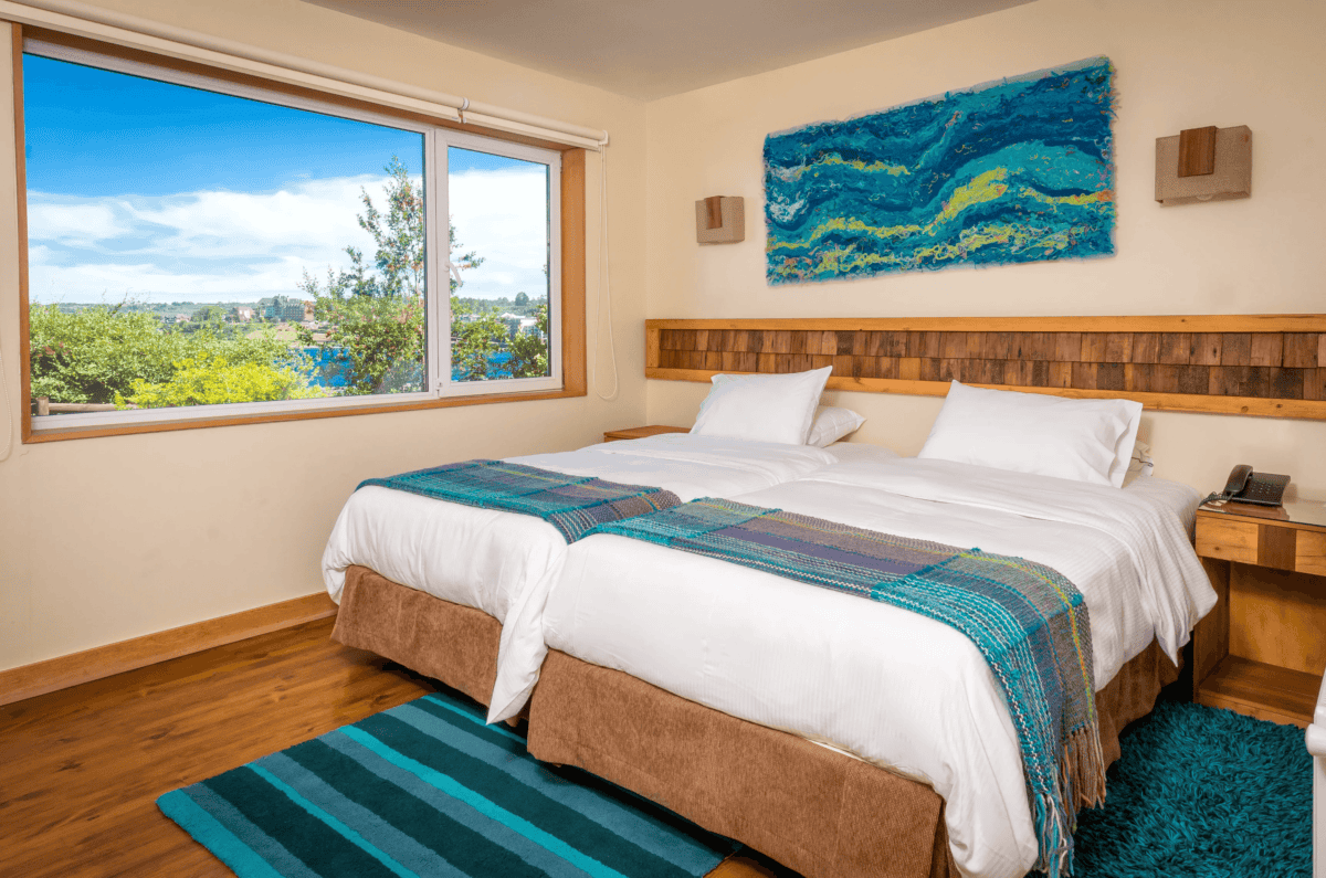 Eco Cabaña Twin en Hotel Cabaña del Lago, acogedora y sostenible, con dos camas y vista espectacular al Lago Llanquihue y los volcanes. Ideal para disfrutar de Puerto Varas con confort y naturaleza